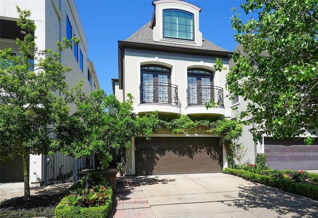 2112 Mcduffie St, Houston, TX 77019 - view of front of home with a balcony, stucco siding, driveway, an attached garage, and french doors