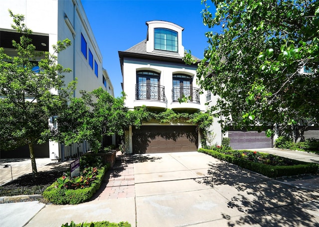 2112 Mcduffie St, Houston, TX 77019 - view of front facade featuring a balcony, stucco siding, driveway, and a garage