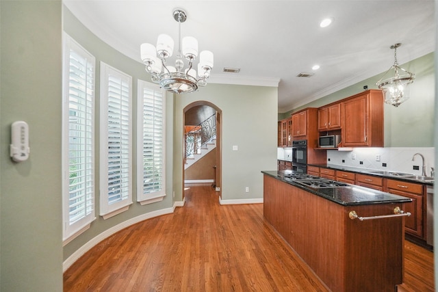 2112 Mcduffie St, Houston, TX 77019 - kitchen with arched walkways, stainless steel appliances, a sink, a chandelier, and plenty of natural light