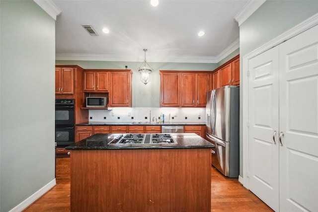 2112 Mcduffie St, Houston, TX 77019 - kitchen with stainless steel appliances, a center island, light wood-style floors, crown molding, and pendant lighting