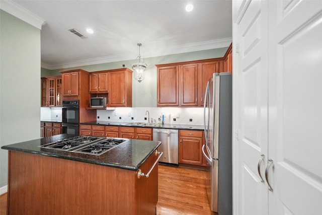 2112 Mcduffie St, Houston, TX 77019 - kitchen featuring stainless steel appliances, a sink, a kitchen island, crown molding, and light wood finished floors