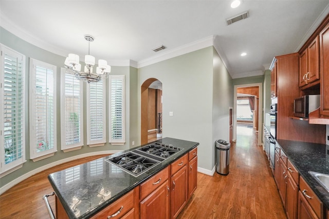 2112 Mcduffie St, Houston, TX 77019 - kitchen with stovetop with downdraft, arched walkways, oven, stainless steel microwave, and light wood-type flooring