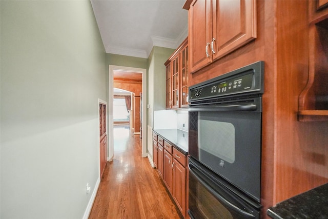 2112 Mcduffie St, Houston, TX 77019 - kitchen with crown molding, light wood-style flooring, brown cabinets, dark stone countertops, and glass insert cabinets