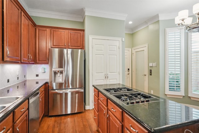 2112 Mcduffie St, Houston, TX 77019 - kitchen featuring stainless steel appliances, wood finished floors, a chandelier, crown molding, and decorative backsplash