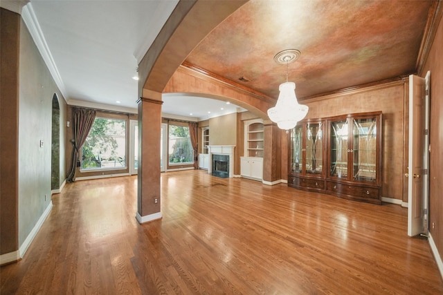 2112 Mcduffie St, Houston, TX 77019 - unfurnished living room with crown molding, a premium fireplace, arched walkways, wood finished floors, and built in shelves