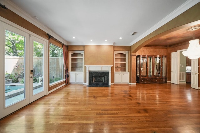 2112 Mcduffie St, Houston, TX 77019 - unfurnished living room featuring crown molding, arched walkways, built in features, wood finished floors, and a high end fireplace
