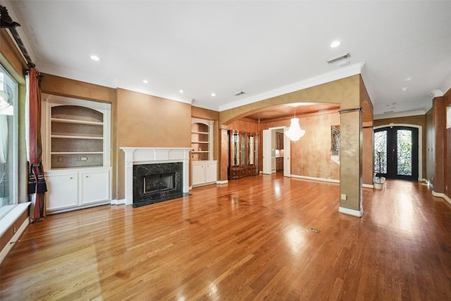 2112 Mcduffie St, Houston, TX 77019 - unfurnished living room with crown molding, built in features, a premium fireplace, wood finished floors, and arched walkways