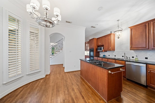 2112 Mcduffie St, Houston, TX 77019 - kitchen featuring appliances with stainless steel finishes, a chandelier, arched walkways, a kitchen island, and wood finished floors