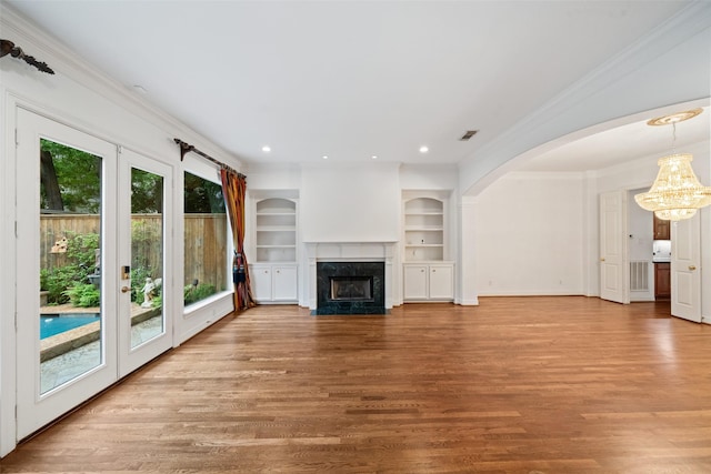2112 Mcduffie St, Houston, TX 77019 - unfurnished living room featuring a chandelier, a fireplace, wood finished floors, built in features, and crown molding