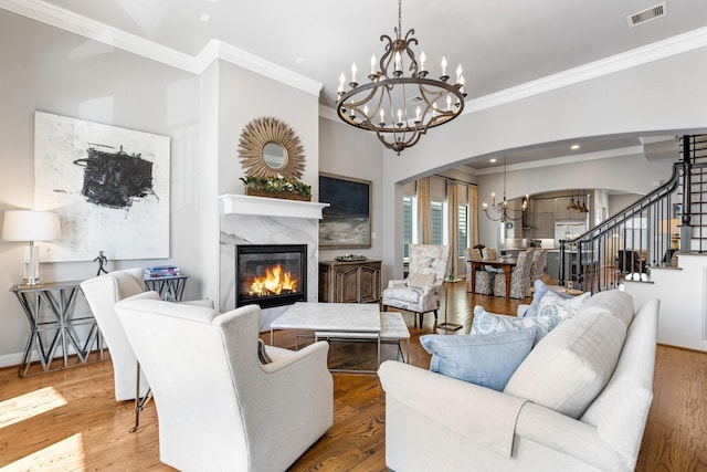 308 W Saulnier St, Houston, TX 77019 - living area with visible vents, a fireplace, wood finished floors, arched walkways, and a notable chandelier