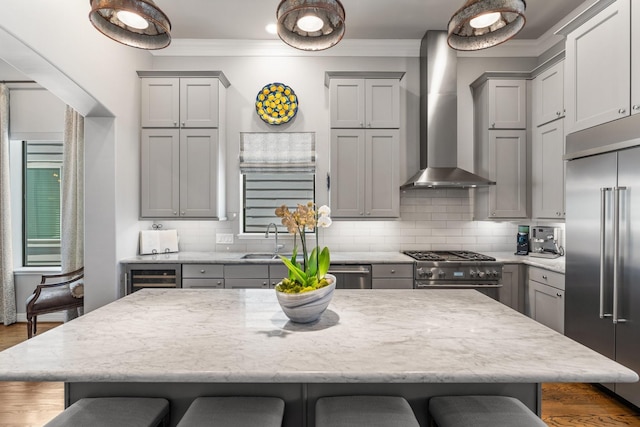 308 W Saulnier St, Houston, TX 77019 - kitchen featuring gray cabinetry, wall chimney exhaust hood, high quality appliances, and a kitchen breakfast bar