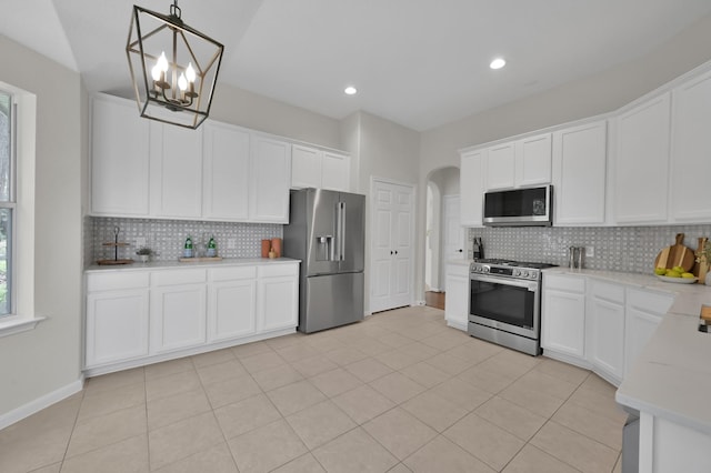 82 S Regan Mead Cir, Montgomery, TX 77382 - kitchen with stainless steel appliances, arched walkways, decorative backsplash, light countertops, and decorative light fixtures