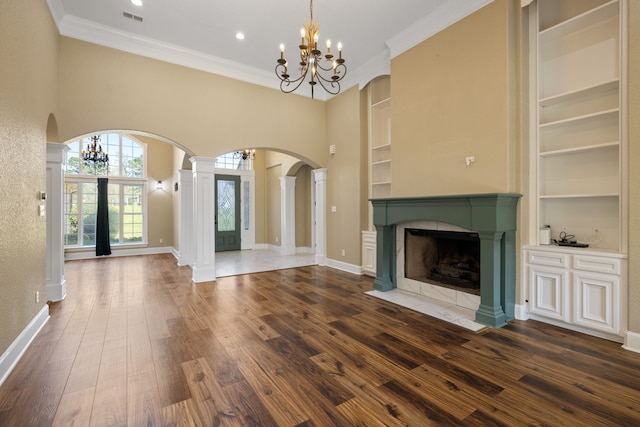 8536 Prince William Ct, Montgomery, TX 77316 - unfurnished living room with a chandelier, built in features, arched walkways, a tiled fireplace, and dark wood-style flooring