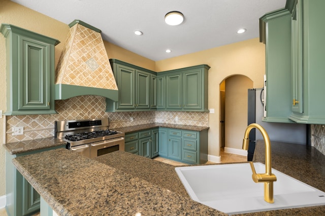 8536 Prince William Ct, Montgomery, TX 77316 - kitchen with range with two ovens, a sink, arched walkways, tasteful backsplash, and premium range hood