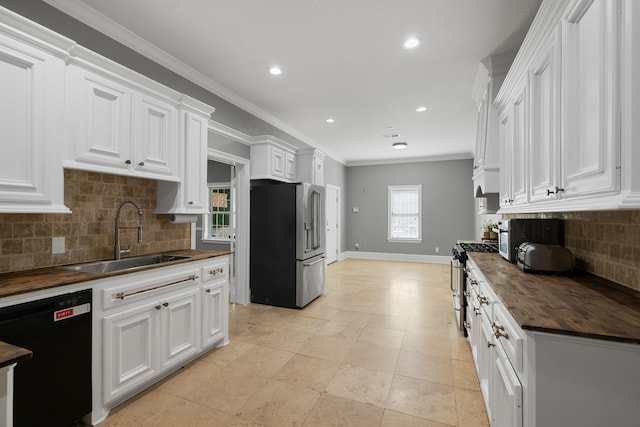 8536 Prince William Ct, Montgomery, TX 77316 - kitchen featuring appliances with stainless steel finishes, butcher block counters, a sink, white cabinetry, and decorative backsplash