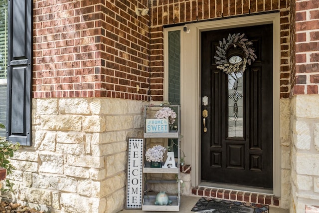 entrance to property with brick siding, stone siding, and covered porch