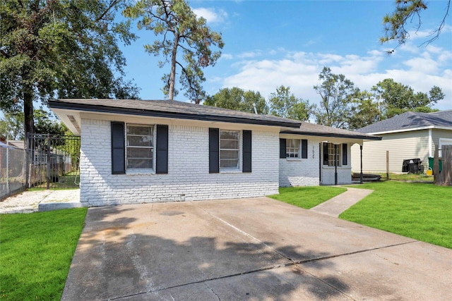 ranch-style home with brick siding, roof with shingles, a front yard, and fence
