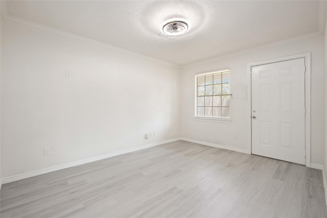 empty room with baseboards, light wood finished floors, and ornamental molding
