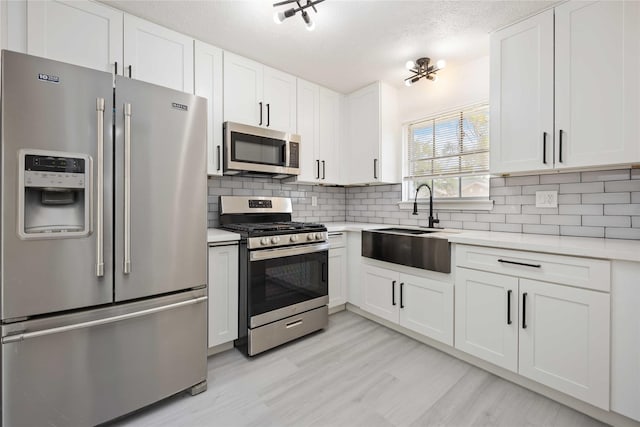 kitchen featuring decorative backsplash, white cabinets, stainless steel appliances, and light countertops