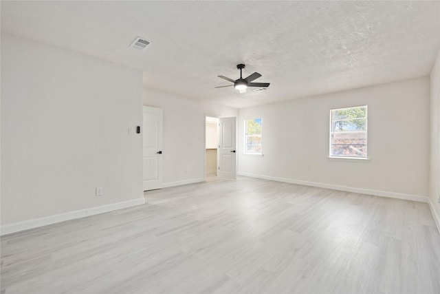 empty room with light wood-type flooring, visible vents, a textured ceiling, baseboards, and ceiling fan