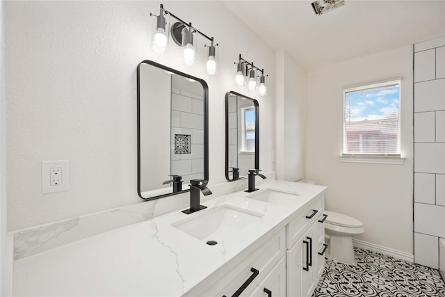 full bath featuring double vanity, tile patterned floors, toilet, and a sink