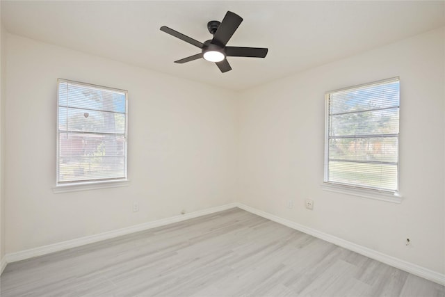 spare room with baseboards, light wood-style flooring, and a ceiling fan