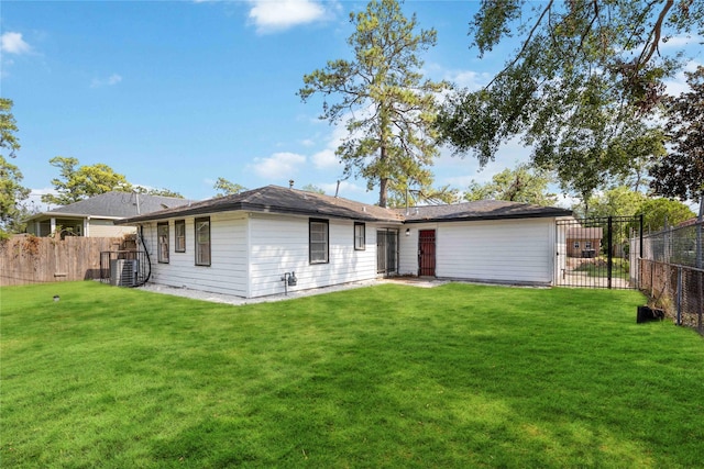 back of property featuring central AC unit, a lawn, and a fenced backyard