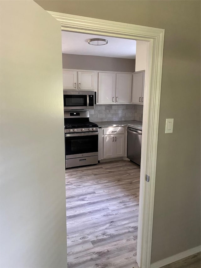 1803 Rampart St, League City, TX 77573 - kitchen featuring white cabinetry, light wood-style flooring, tasteful backsplash, and appliances with stainless steel finishes