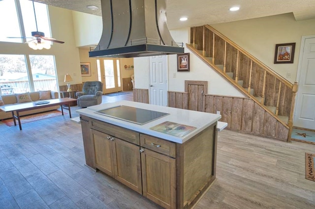 122 Vivian St, Brazoria, TX 77422 - kitchen with island range hood, black electric cooktop, light wood-style floors, ceiling fan, and a towering ceiling