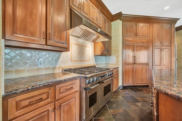 2023 Greenwood Oaks Dr, Houston, TX 77062 - kitchen with under cabinet range hood, double oven range, dark stone countertops, backsplash, and stone tile floors