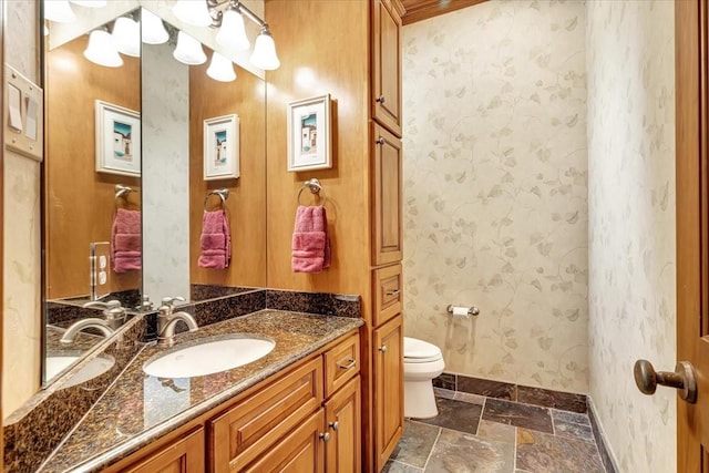 2023 Greenwood Oaks Dr, Houston, TX 77062 - bathroom featuring vanity, stone tile floors, baseboards, wallpapered walls, and toilet