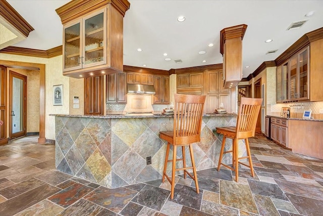 2023 Greenwood Oaks Dr, Houston, TX 77062 - kitchen featuring stone tile floors, stone countertops, under cabinet range hood, and ornamental molding