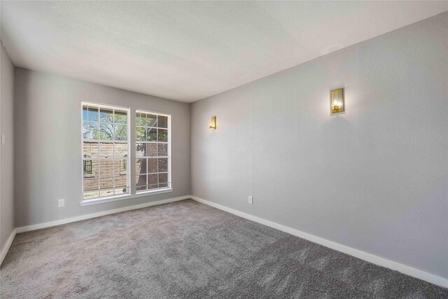 spare room with baseboards, carpet floors, and a textured ceiling