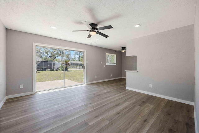 unfurnished living room featuring wood finished floors, baseboards, recessed lighting, ceiling fan, and a textured ceiling