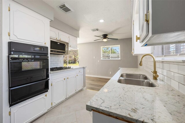 kitchen with stainless steel microwave, white cabinetry, visible vents, and a sink