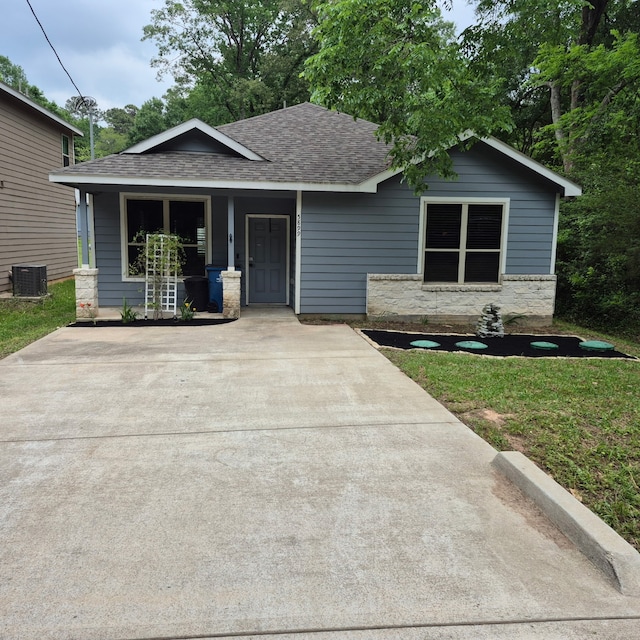 5899 Skylane Dr, Montgomery, TX 77316 - view of front facade with central AC, a shingled roof, covered porch, a front yard, and stone siding