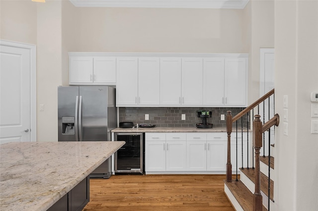 4314 Gibson St Unit A, Houston, TX 77007 - kitchen featuring wine cooler, decorative backsplash, ornamental molding, stainless steel fridge, and white cabinetry