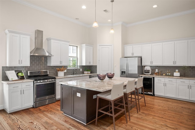 4314 Gibson St Unit A, Houston, TX 77007 - kitchen featuring beverage cooler, appliances with stainless steel finishes, wall chimney range hood, a kitchen island, and backsplash