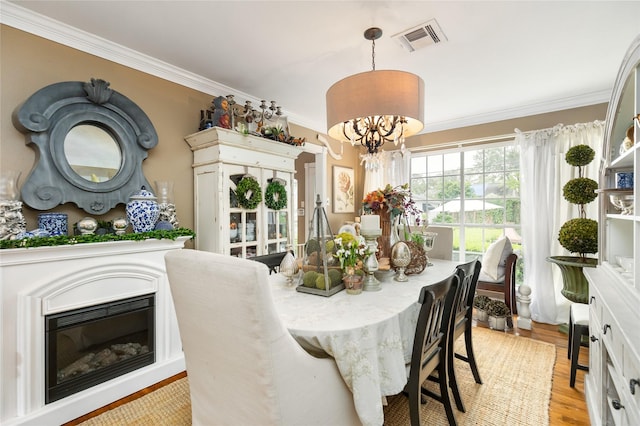 834 Lamonte Ln, Houston, TX 77018 - dining room featuring visible vents, a chandelier, crown molding, light wood finished floors, and a glass covered fireplace
