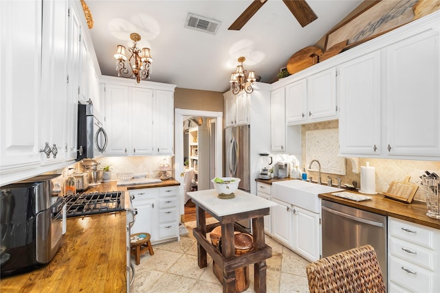834 Lamonte Ln, Houston, TX 77018 - kitchen featuring white cabinetry, visible vents, a sink, stainless steel appliances, and wood counters