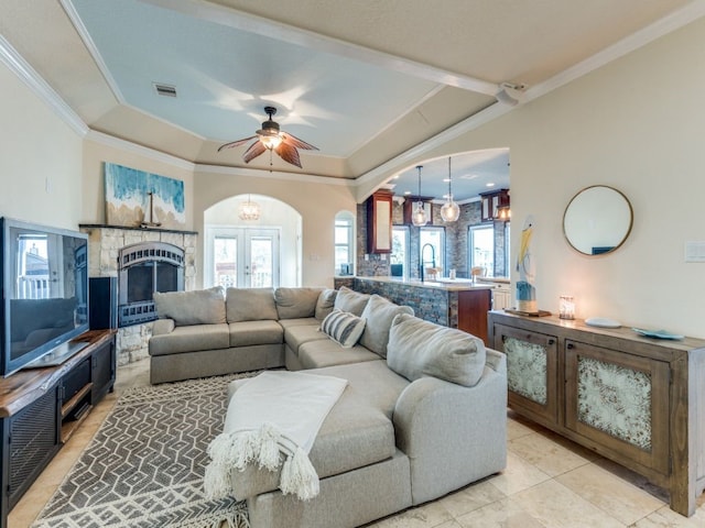 living area featuring a wealth of natural light, arched walkways, a raised ceiling, and crown molding