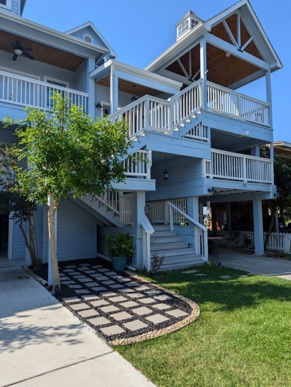 raised beach house featuring a front lawn and stairway