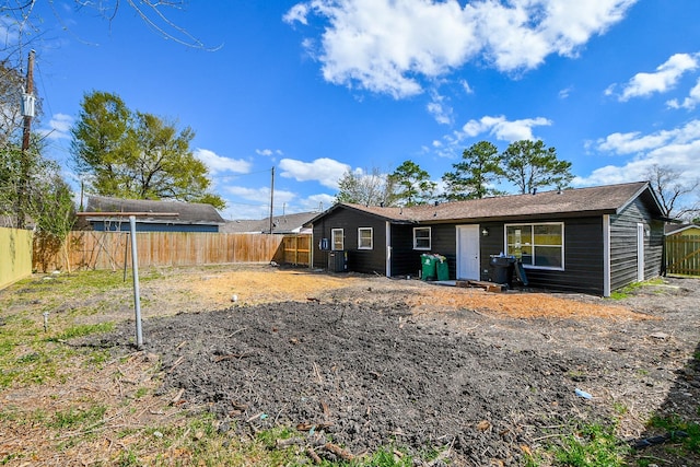 rear view of house featuring central air condition unit and a fenced backyard