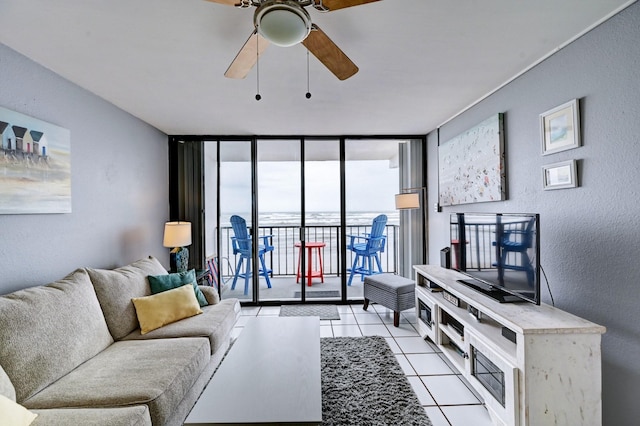 living area with light tile patterned floors, floor to ceiling windows, ceiling fan, and a textured wall