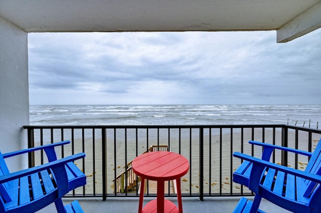 balcony featuring a view of the beach and a water view