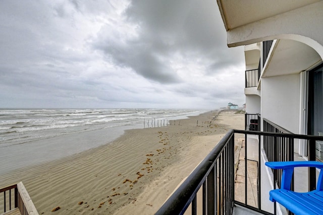 balcony featuring a view of the beach and a water view