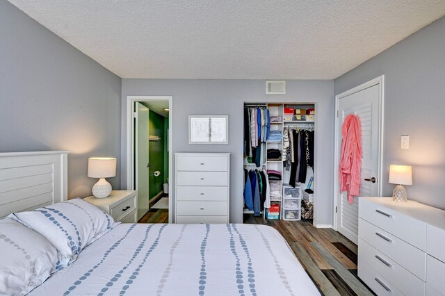 bedroom with visible vents, connected bathroom, wood finished floors, a closet, and a textured ceiling