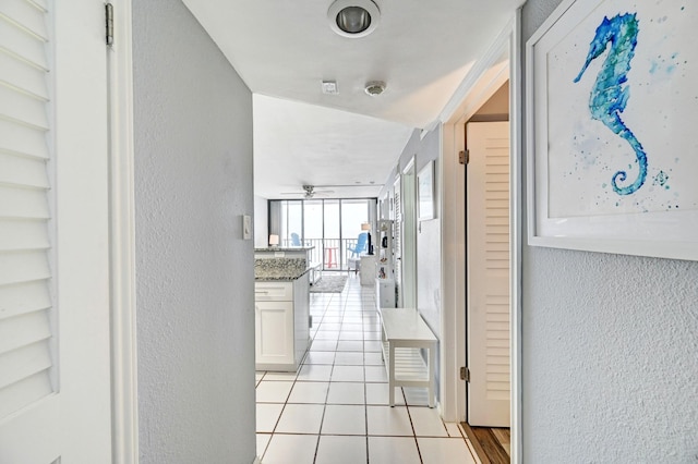 corridor featuring light tile patterned floors and a textured wall