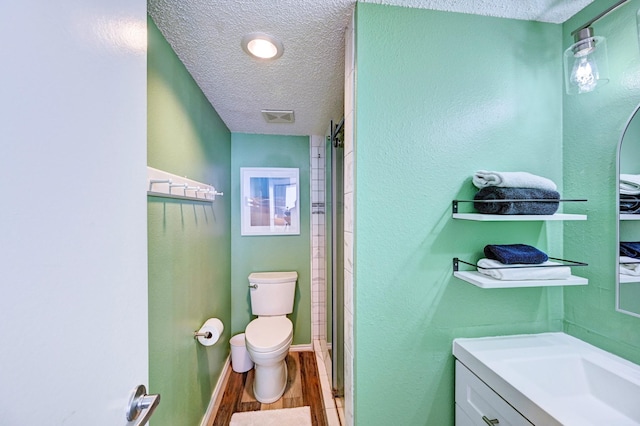 bathroom with visible vents, toilet, vanity, wood finished floors, and a textured ceiling