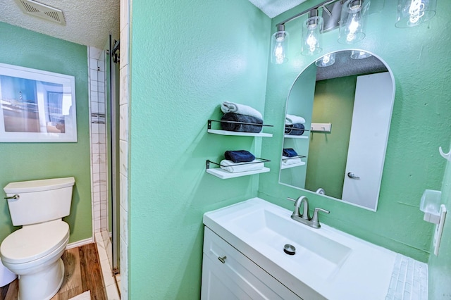 full bath with visible vents, toilet, vanity, wood finished floors, and a textured ceiling